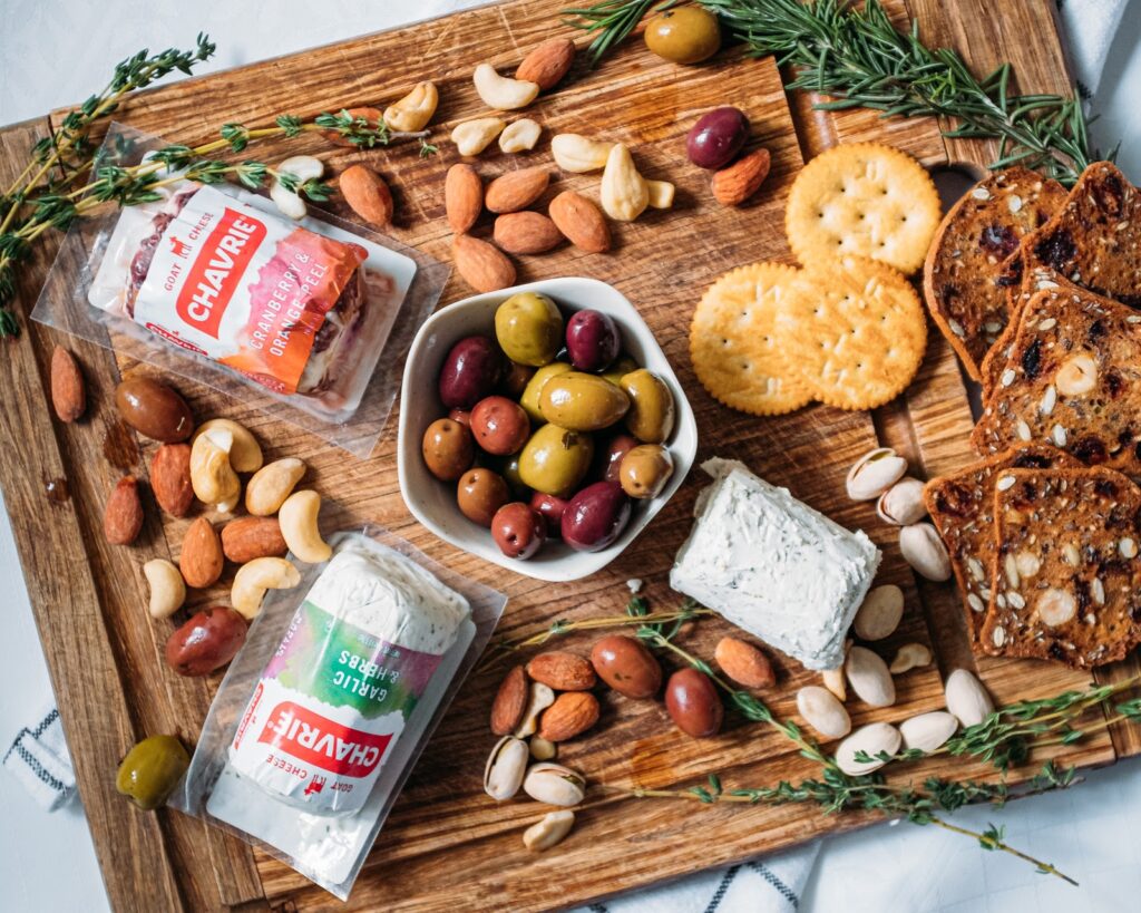 cheese board with chavrie garlic and herbs cranberry & orange peel, crackers, nuts, olives