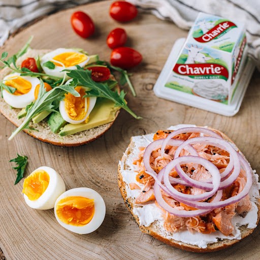 bagels topped with Chavrie goat cheese pyramid, avocado and eggs and lox and onions