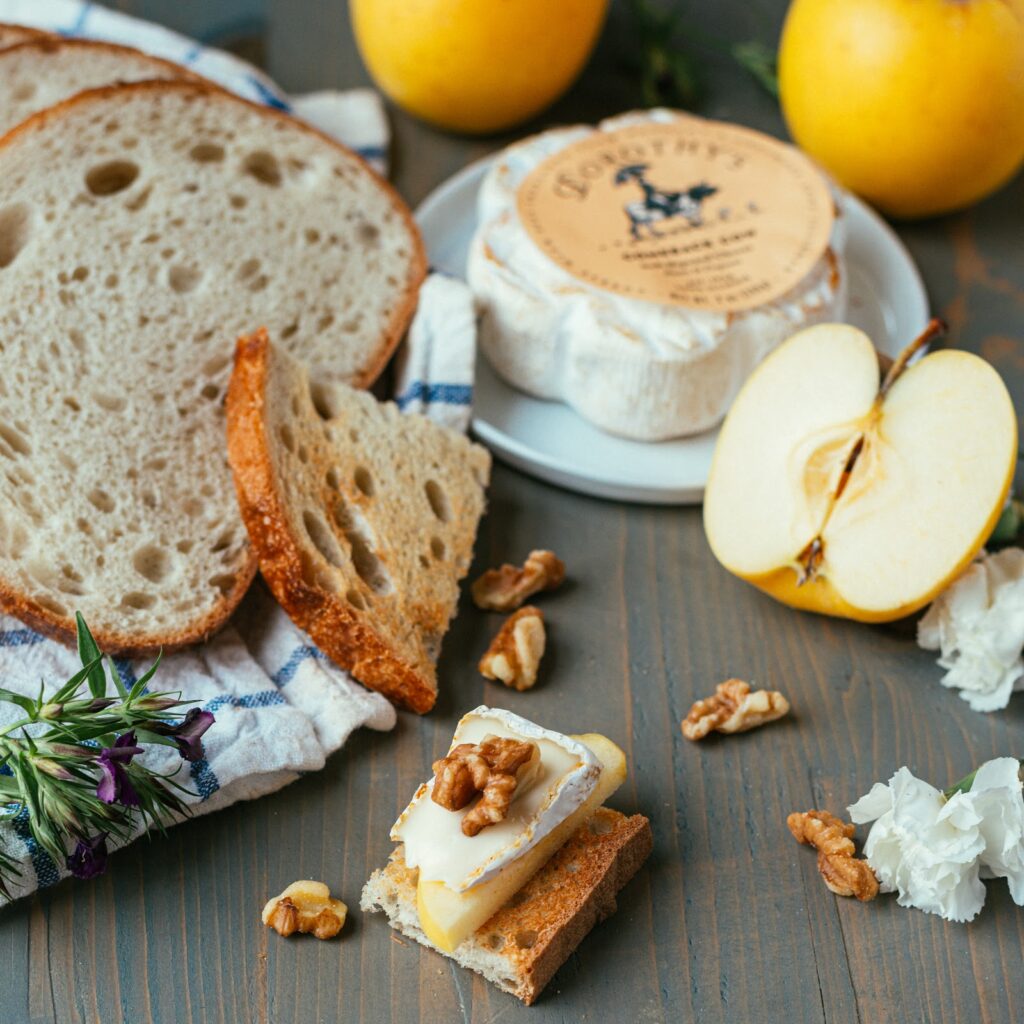 A piece of toasted bread with a slice of apple, dorothys comeback cow and a walnut on top